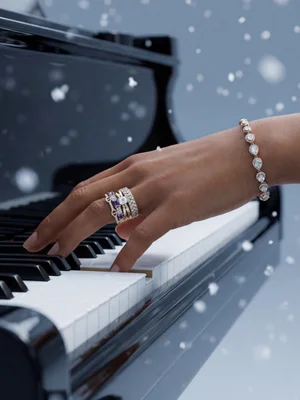 White-metal line bracelet on a hand at a black piano