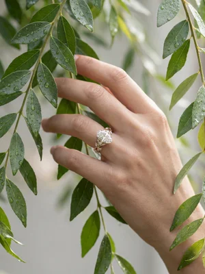 White-metal ring on a hand among leaves