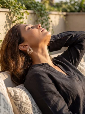 Gold earrings on a model resting on cushions