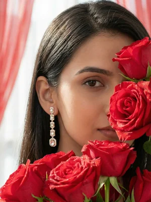 Long drop earrings behind red roses