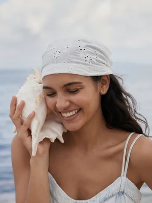 Small heart stud on a model holding a shell at the beach