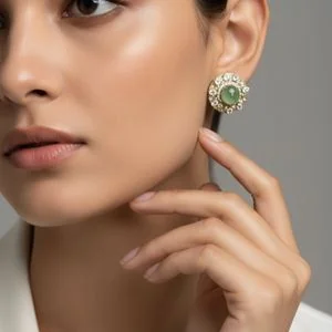 Model touching her ear, wearing a green gemstone stud at its real size