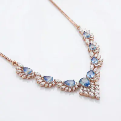 Blue-stone statement necklace in a rose-gold tone on white, angled close crop