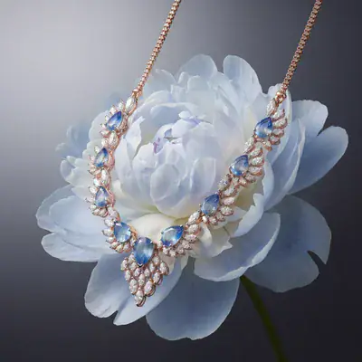Blue-stone necklace laid over a pale blue peony
