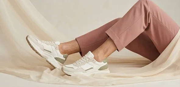 Footwear look on a model in white sneakers, lounging on a linen backdrop, an AI photoshoot by Kaptured.AI