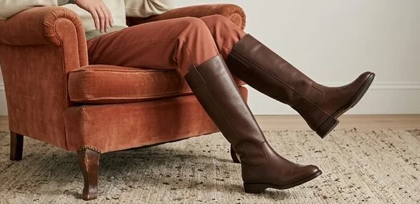 Footwear look on a model in tall leather boots, seated in an armchair, an AI photoshoot by Kaptured.AI