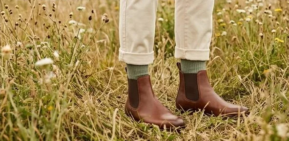 Footwear look on a model in leather boots standing in long grass, an AI photoshoot by Kaptured.AI