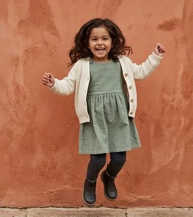 Kidswear look on a model moving past a terracotta wall, an AI photoshoot by Kaptured.AI