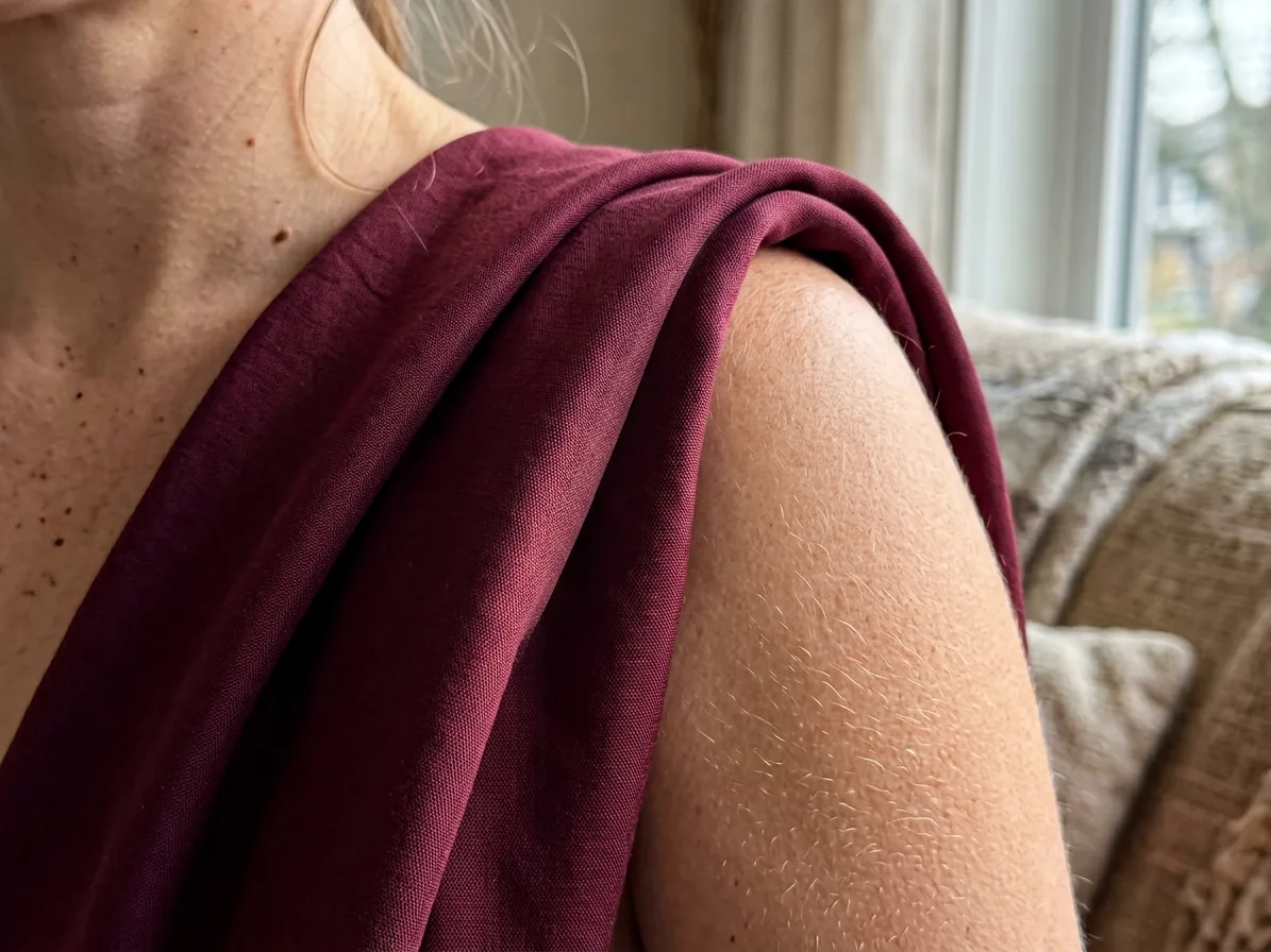 Close-up of maroon silk falling in long folds from a woman's shoulder, made with AI