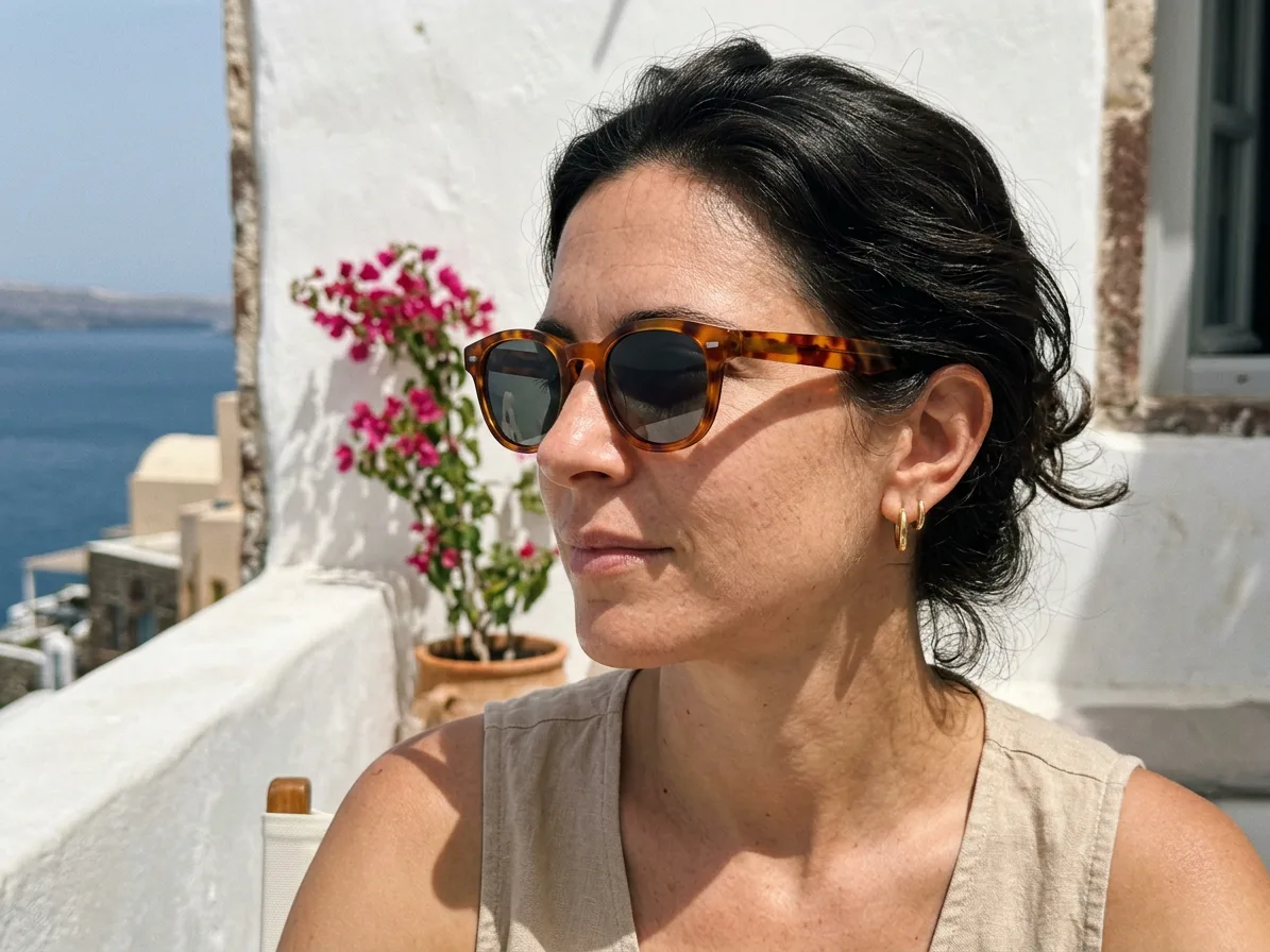 A woman wearing the sunglasses on a whitewashed terrace, made with AI